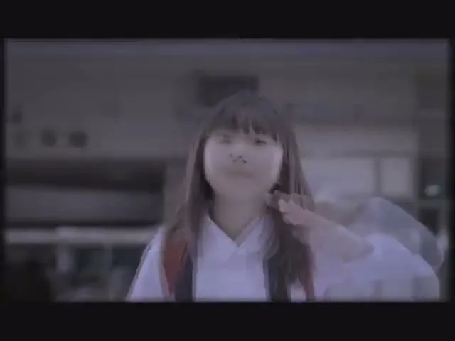 A young Asian girl with long hair and a backpack looks at the camera, then turns her head and walks away in a blurry, dark setting.