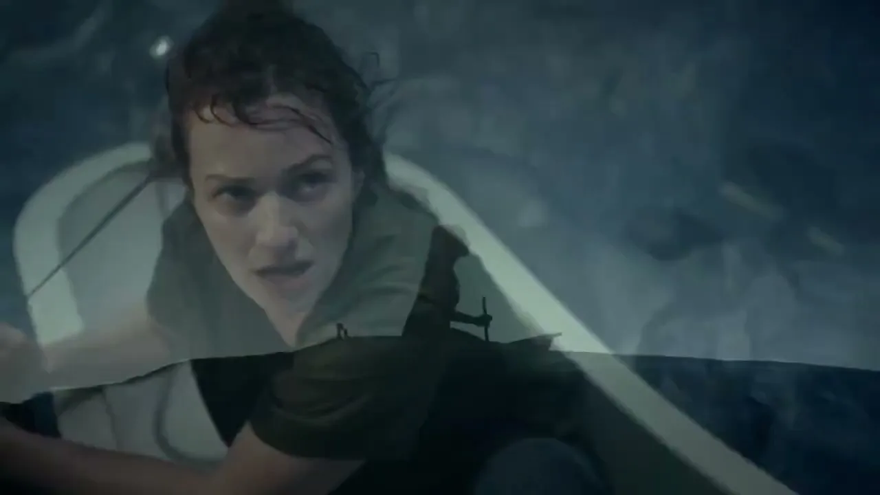A woman with wet hair and a green shirt looks up with a worried expression, as if she is in a boat on rough water.