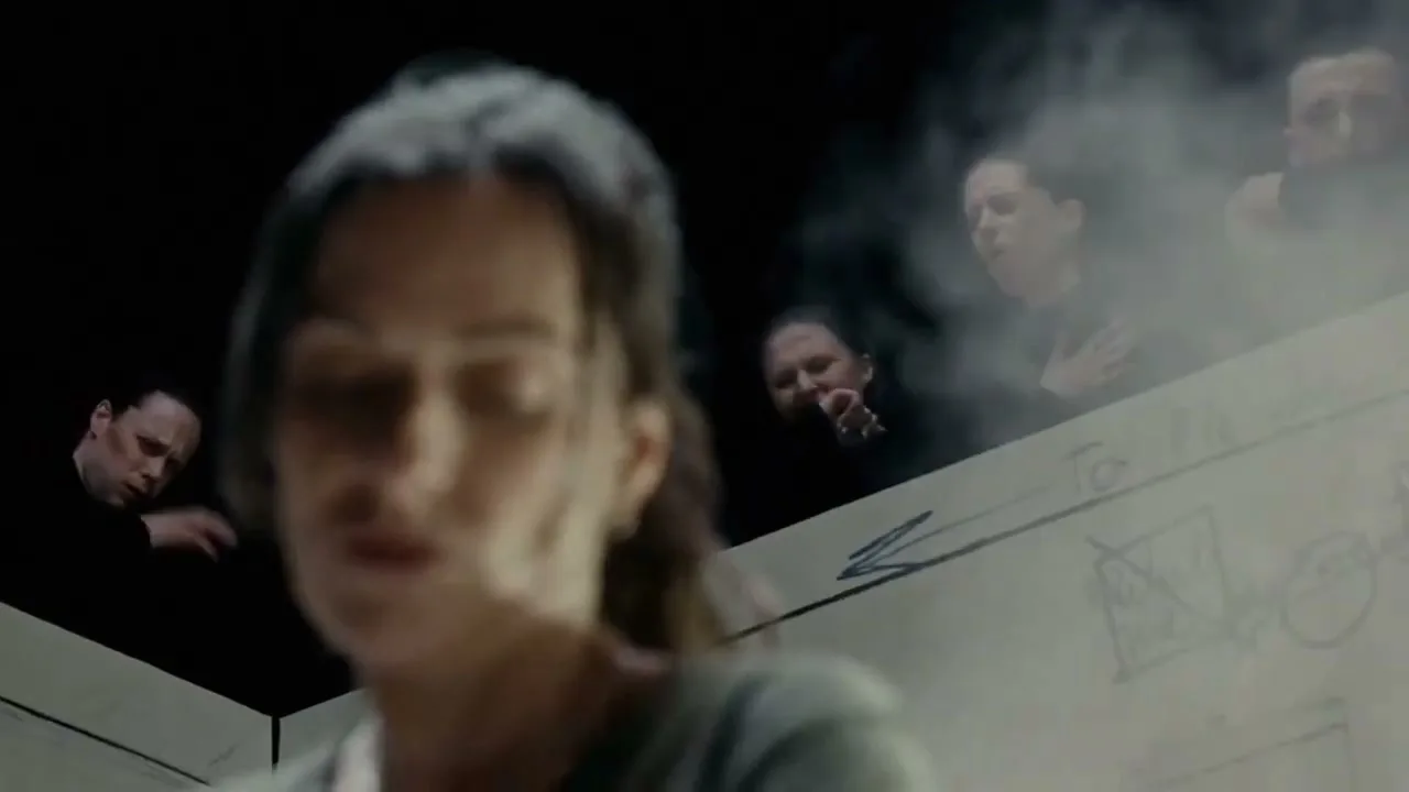 A woman in the foreground looks down, while several people in the background look up from a dark void, some coughing in smoke.