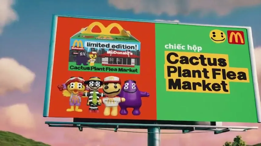 A large billboard advertising the McDonald's Cactus Plant Flea Market box, featuring cartoon characters and a happy meal box, stands against a cloudy sky.