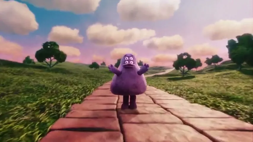 A purple, four-eyed creature with a wide mouth and small arms walks down a brick path in a green, grassy field under a pink and blue sky with fluffy clouds.