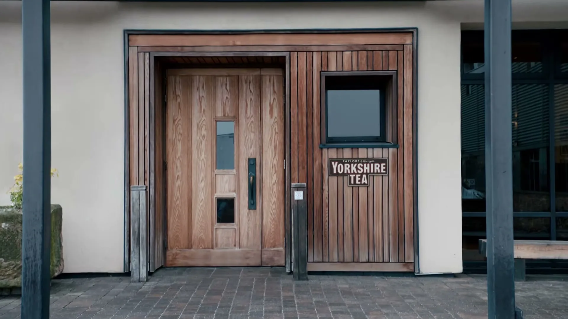 A wide shot of the entrance to the Yorkshire Tea building, featuring a wooden door and a sign with the brand's logo.