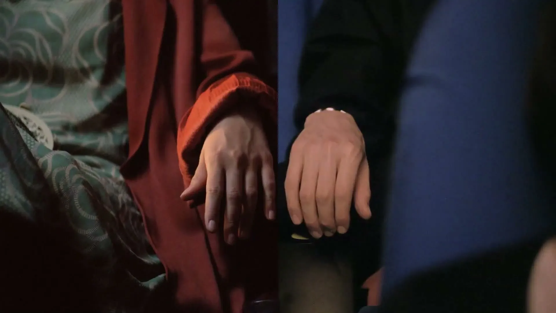 Two hands, one in a red sleeve and the other in a black sleeve, are shown side-by-side, almost touching.