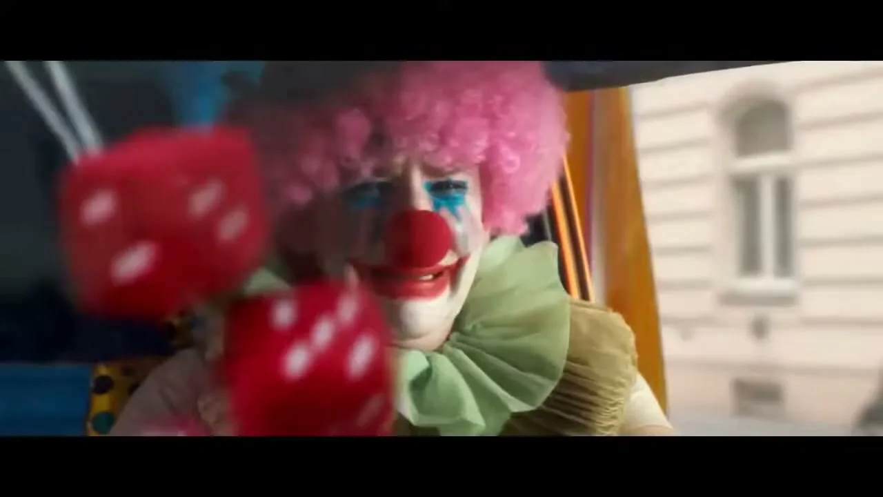 A clown with a pink wig and red nose screams in terror while driving a car, as red dice and a pink polka-dot scarf fly past their face.