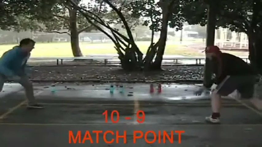 Two young men play a game with bottles on a wet outdoor court, with "10 - 9 MATCH POINT" text overlaid.