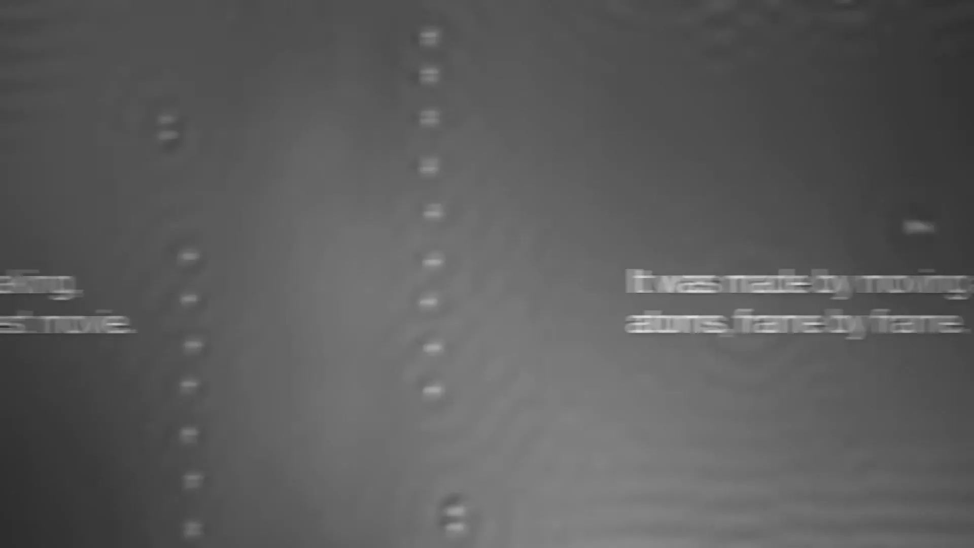 A microscopic view of atoms on a surface, with text appearing and disappearing to explain the process of creating the world's smallest movie.