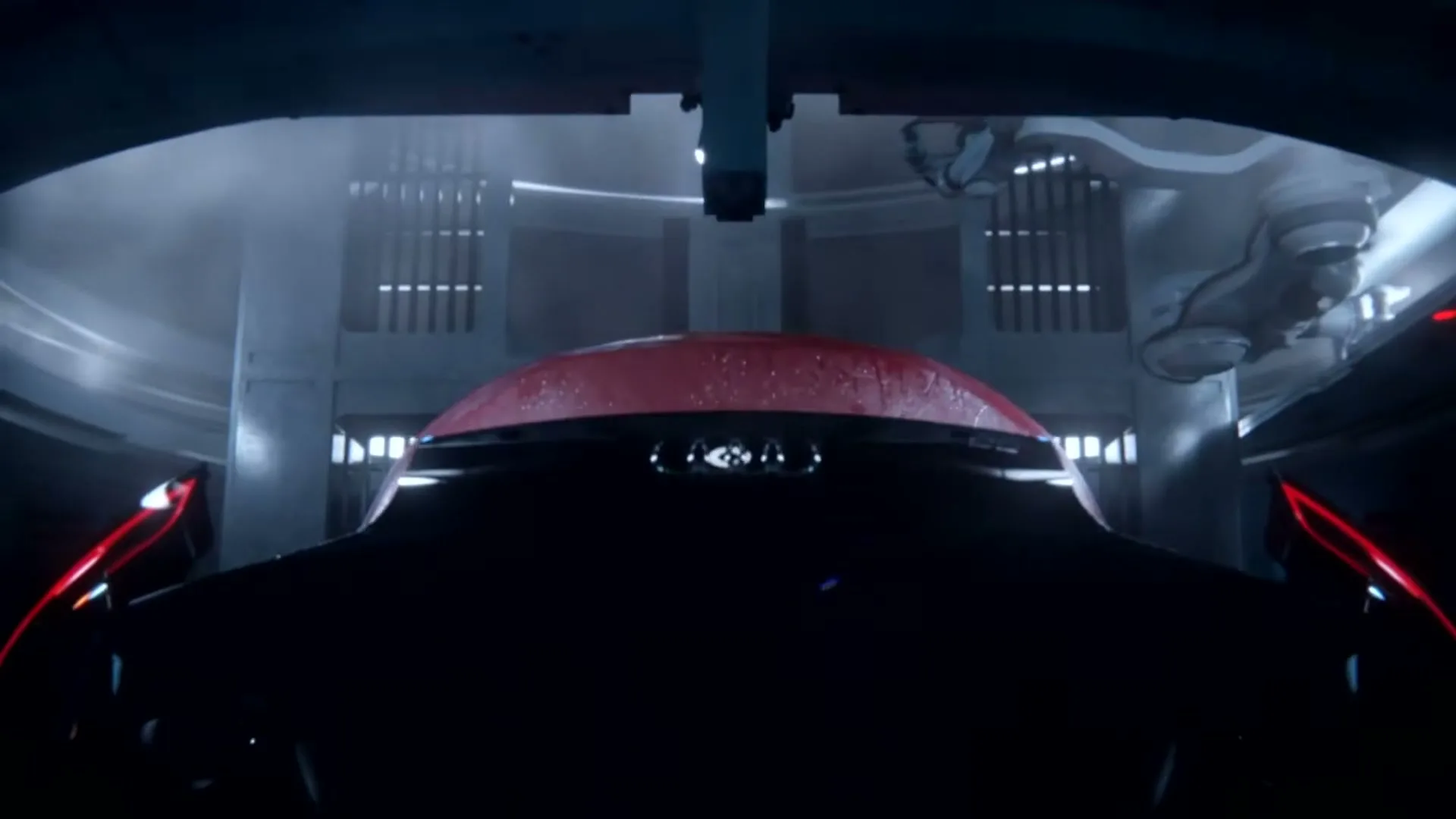 A dark, sleek car with a red roof is seen from behind, being worked on by robotic arms in a futuristic, industrial setting.