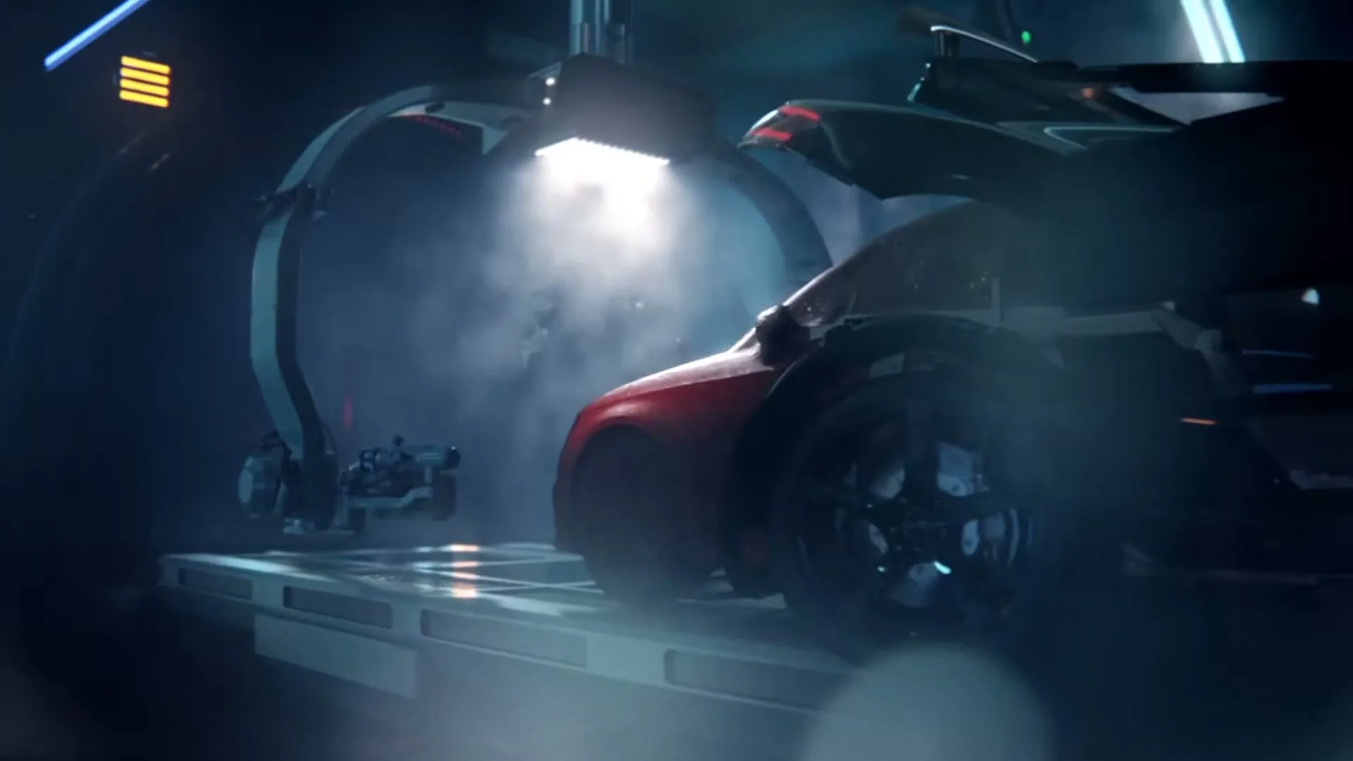 A red car is being assembled by robotic arms in a futuristic, dark factory setting, with bright light shining on the vehicle.