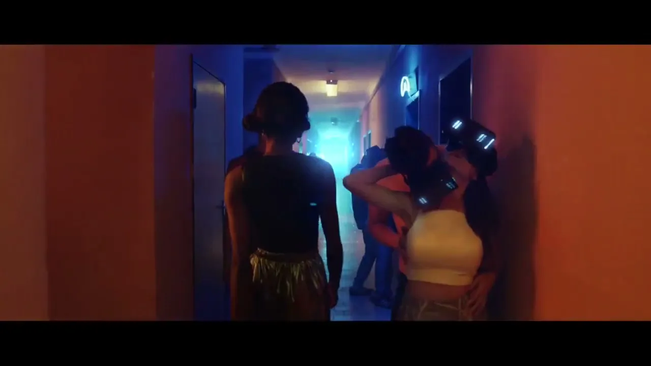 A diverse group of young people walk down a dimly lit hallway, some wearing VR headsets, in a futuristic setting.