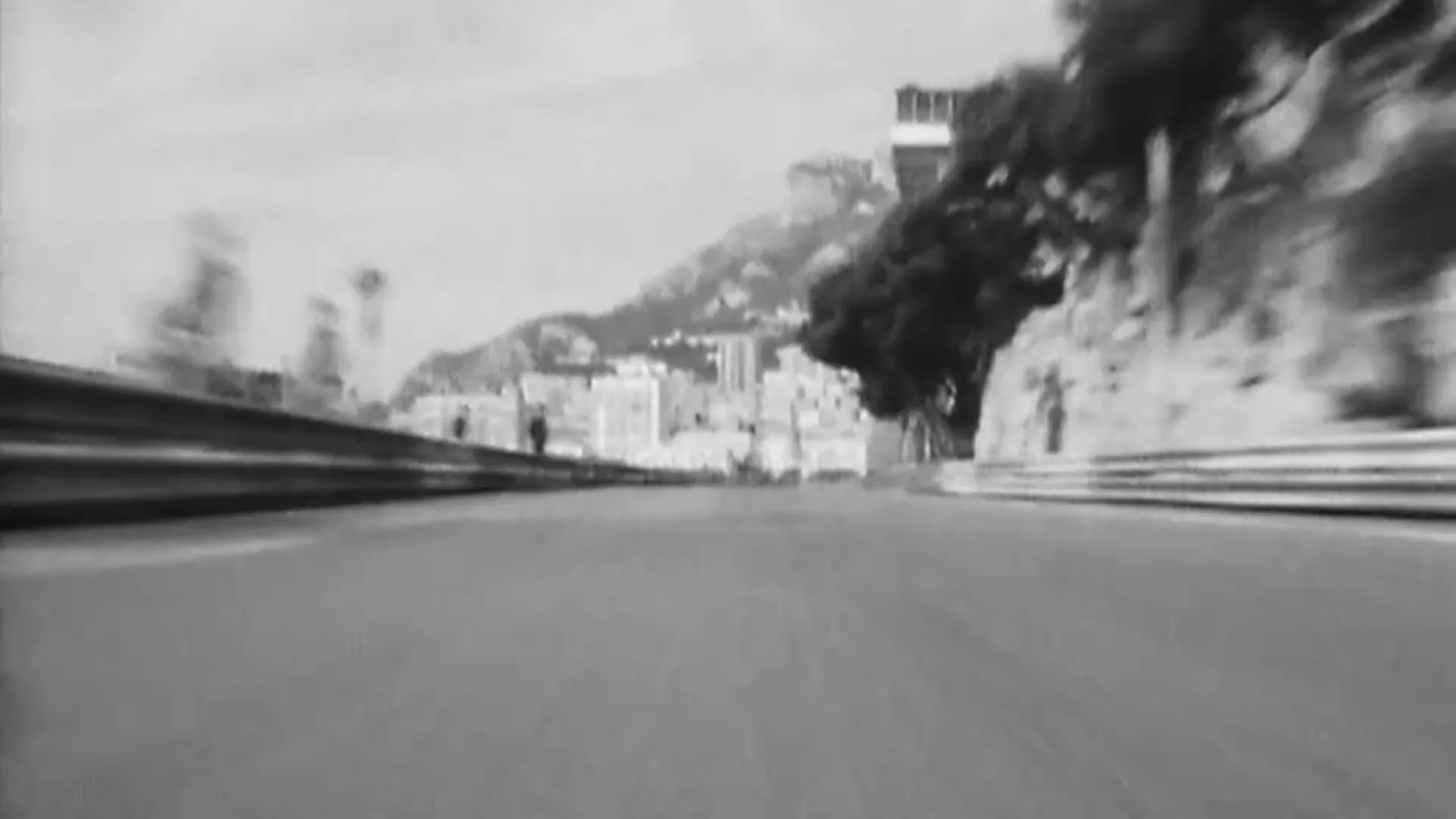A black and white archival shot shows a race car speeding through a tunnel and then on an outdoor track.