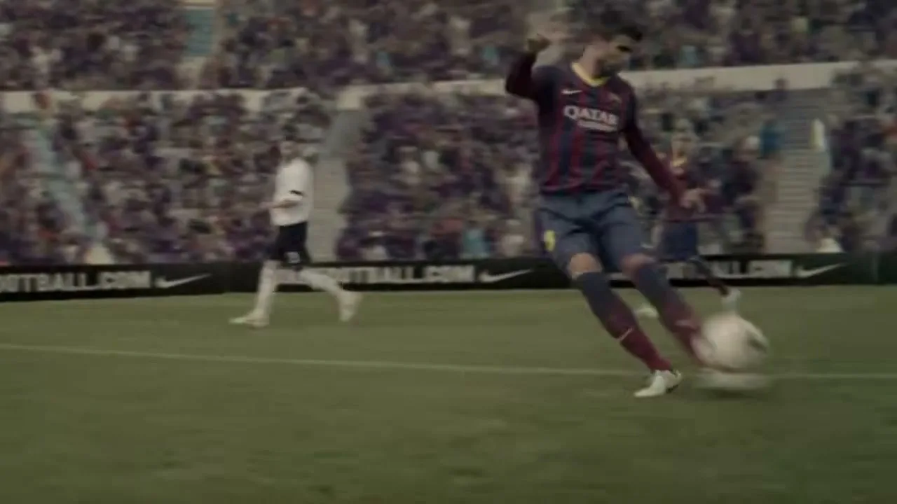 A young male soccer player in a yellow jersey and green shorts performs a bicycle kick in a stadium, with other players and spectators in the background.
