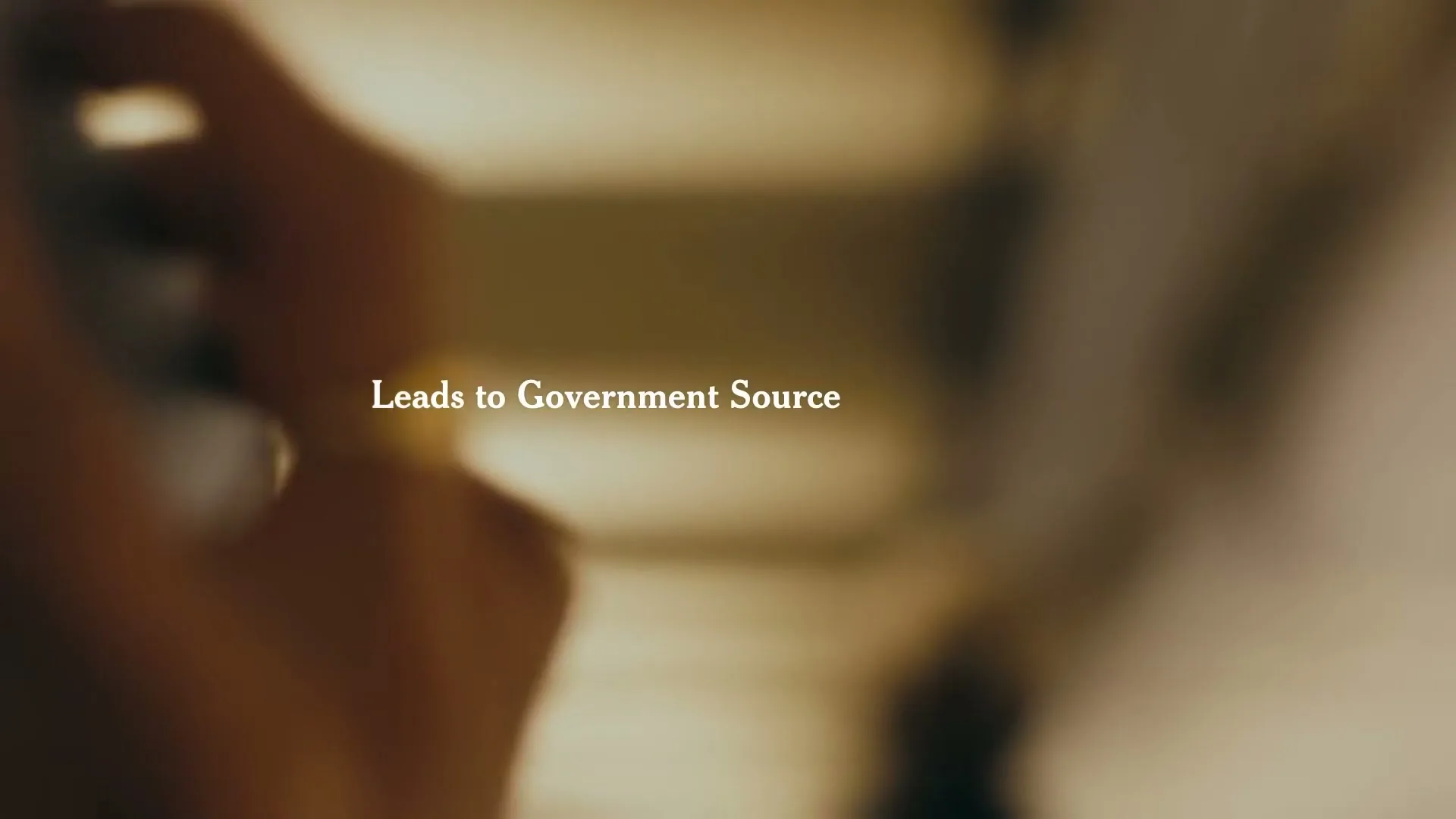 A blurry, out-of-focus shot of people in an interior setting, with the text "Leads to Government Source" overlaid on the screen.