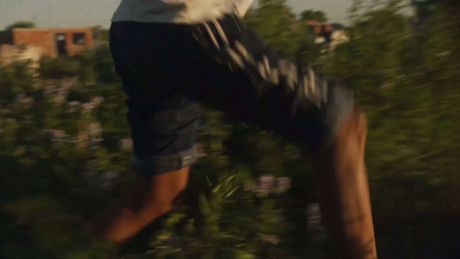 A person with a bloody knee runs through a field of tall grass and then enters a dark, dilapidated wooden structure.