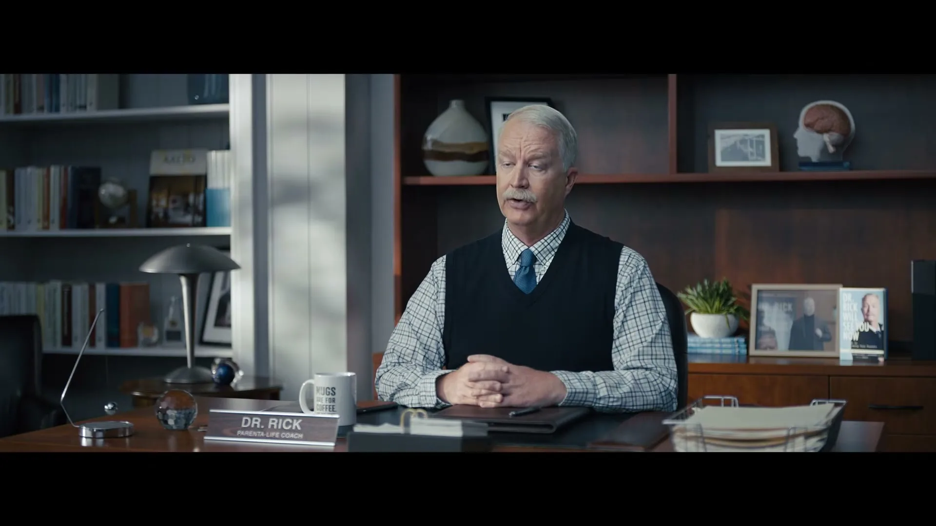 Dr. Rick, a middle-aged man with a mustache, sits at his desk, speaking to the camera in his office.