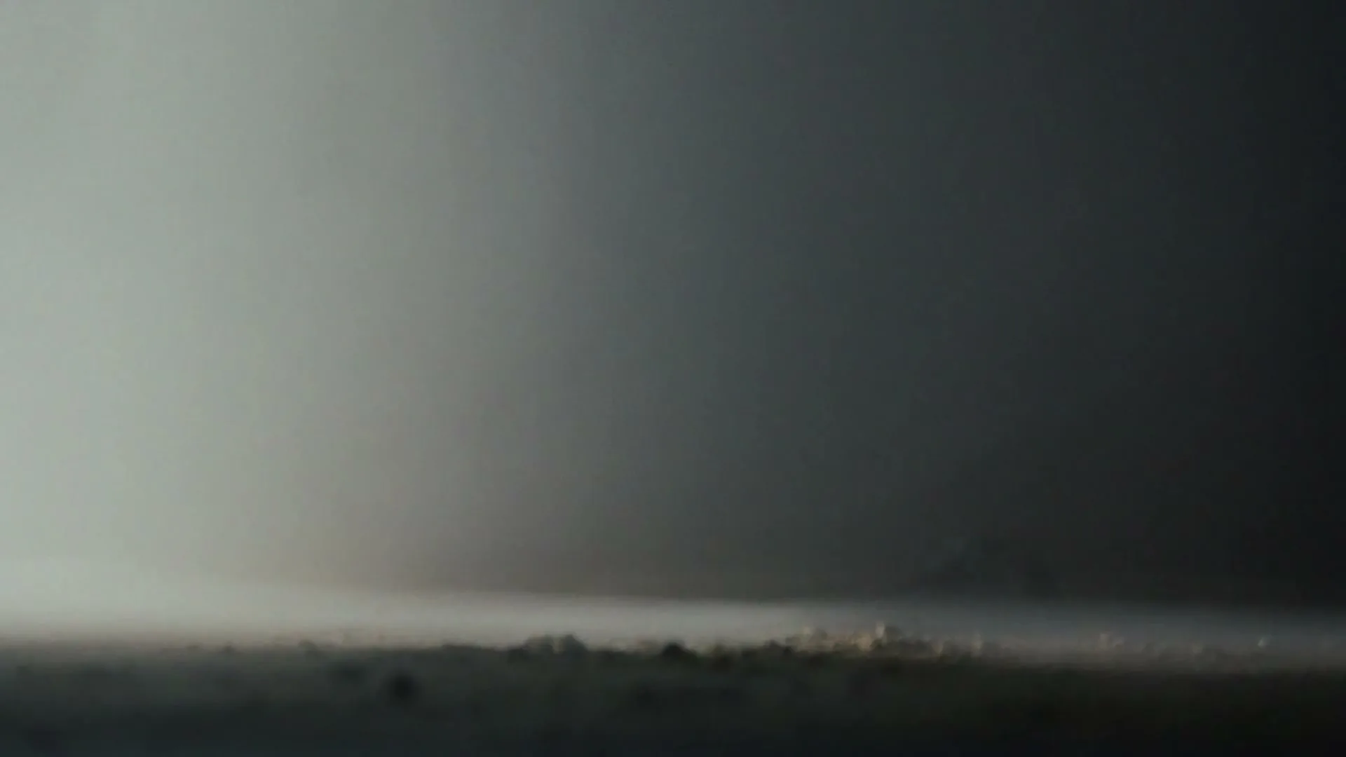 A wide shot shows a dark, smoky landscape with a faint light source on the left, creating a mysterious and ominous atmosphere.