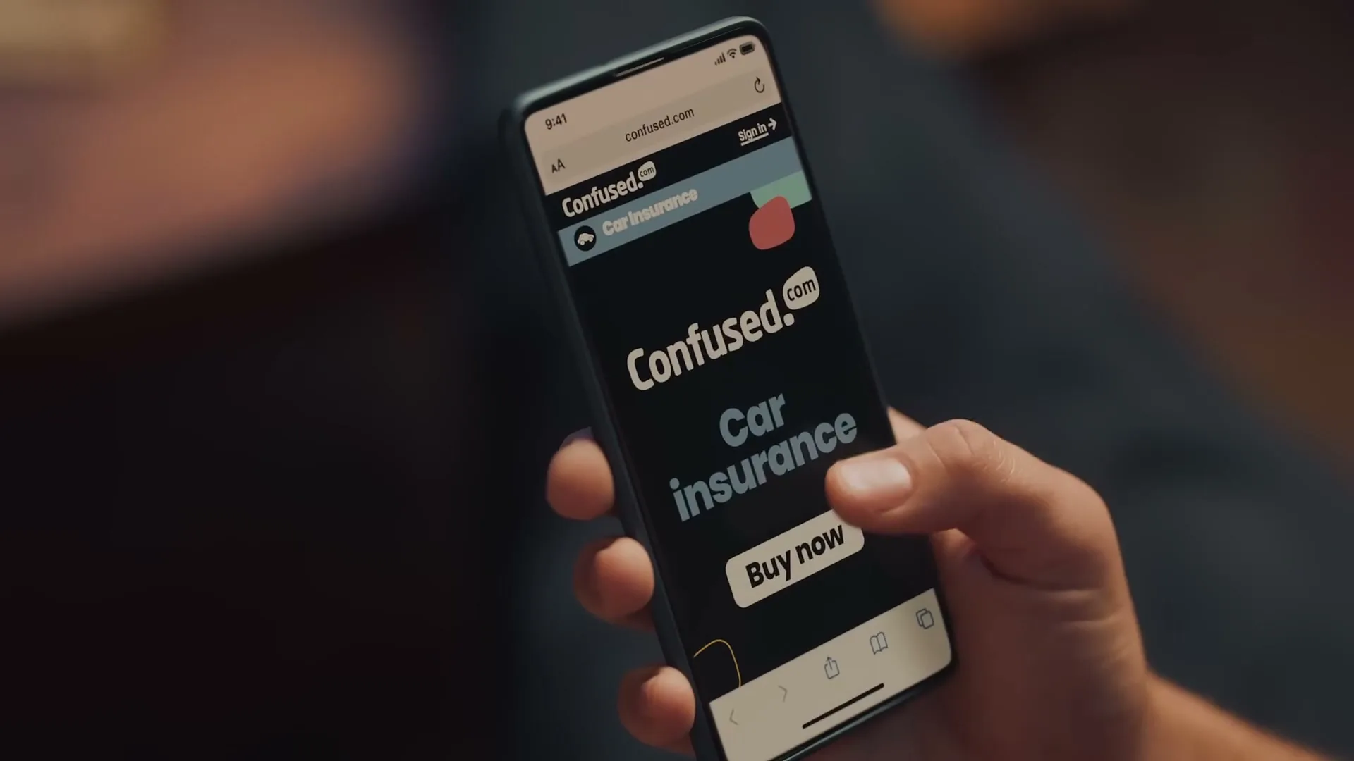 A person's hand holds a smartphone displaying the Confused.com website for car insurance, with the text changing to "You've saved" on screen.