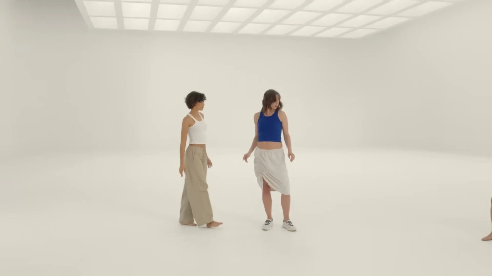 A young woman with short, curly hair looks around a bright, white studio, then dances with two other women, before looking up thoughtfully.