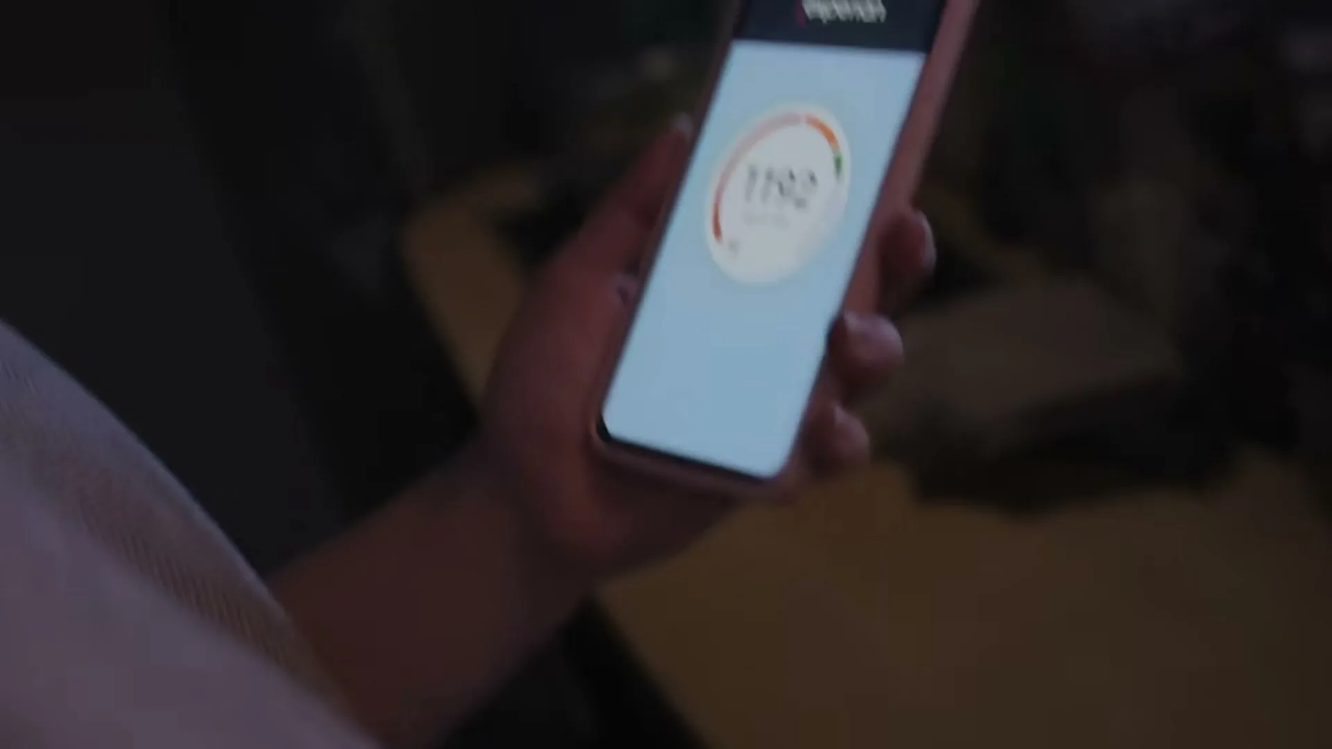 A person's hand reaches into a drawer, pulls out a phone, and checks their Experian credit score on the screen.
