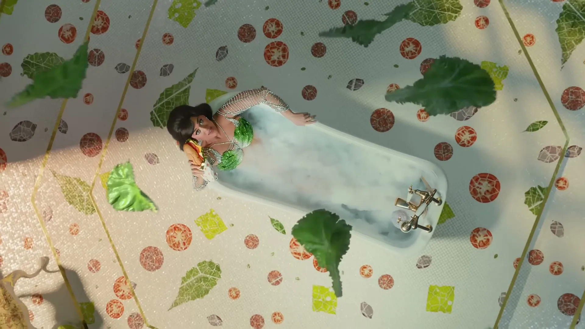 Katy Perry, dressed in a mermaid-like outfit, is seen from an overhead perspective, eating a sandwich while relaxing in a bathtub filled with bubbles.