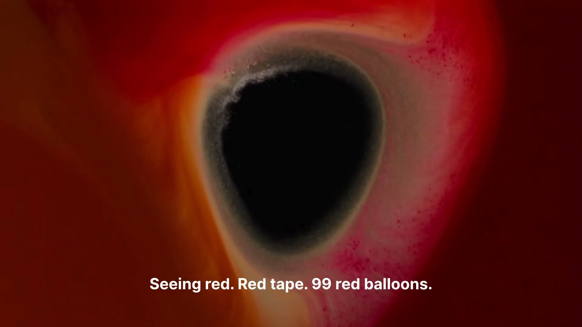 A macro shot shows red and orange ink swirling around a black, eye-like void, with white text appearing at the bottom of the frame.