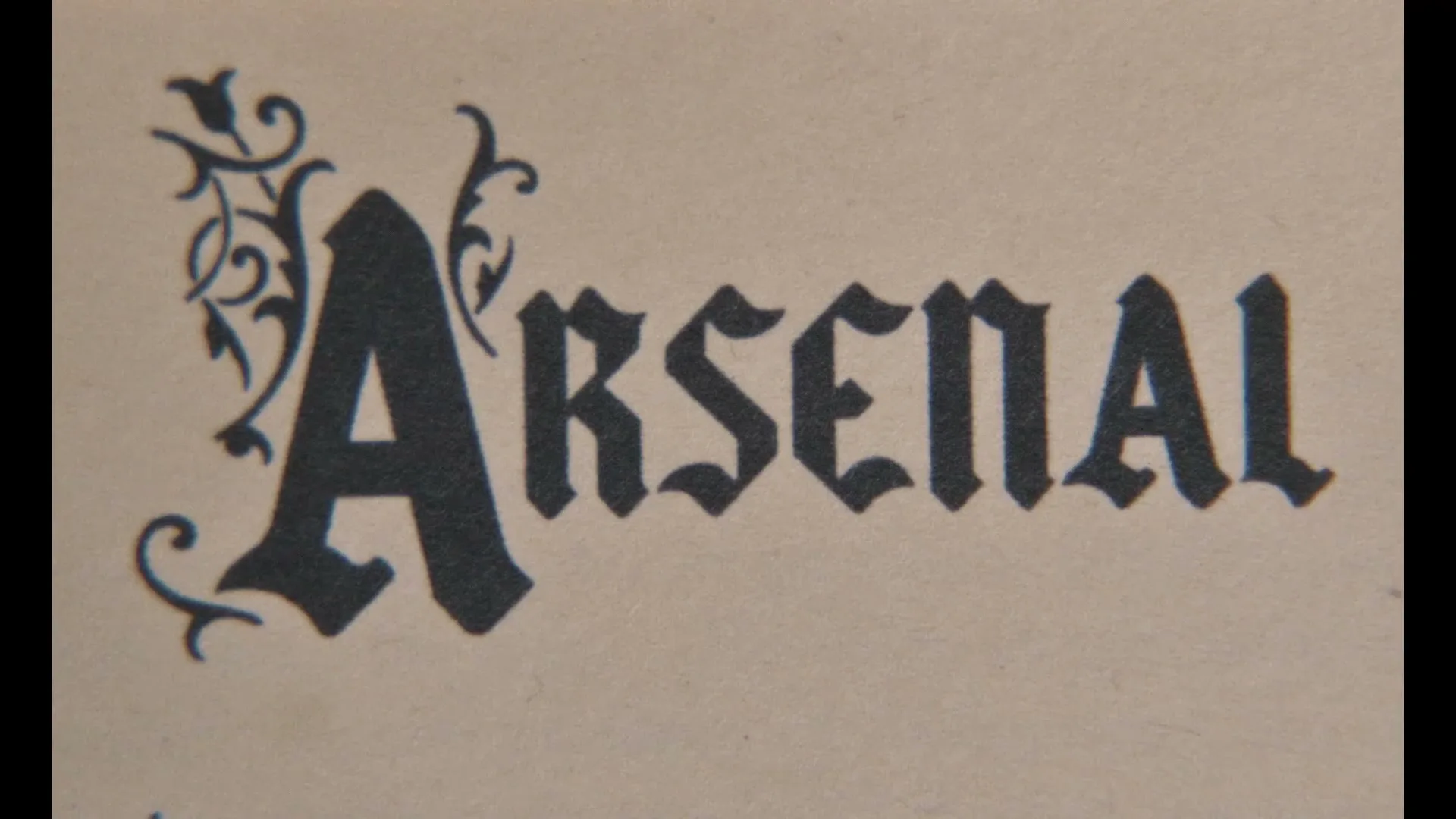 The word "Arsenal" is displayed in an ornate, gothic-style font on a textured, light brown background.