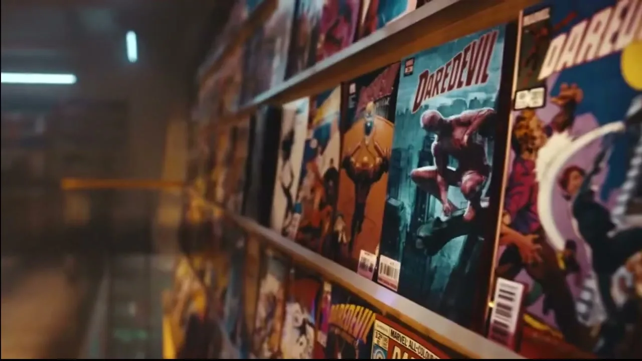 A close-up shot of a shelf filled with various comic books, with a blue light effect on the left side.