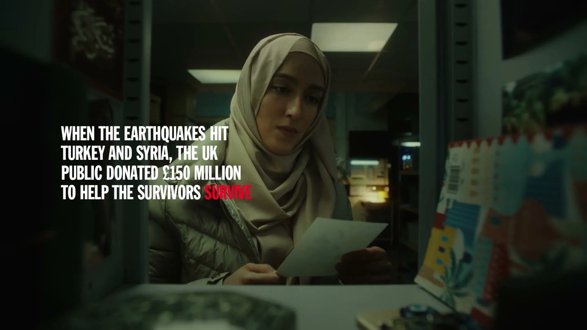 A young woman in a hijab and puffer jacket looks at a drawing and puts it in a locker, then closes the locker door.