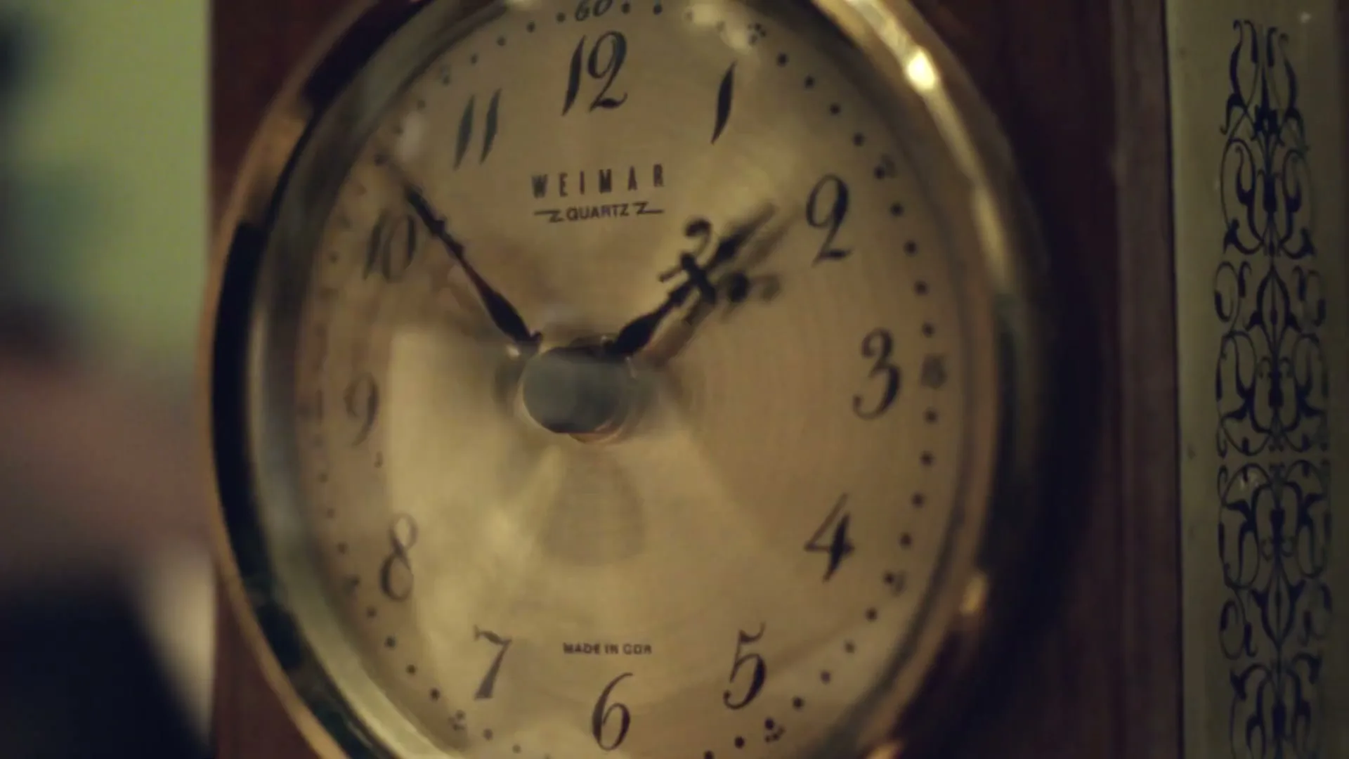 A close-up shot of an old, ornate wooden clock with a gold face and black numbers, its hands rapidly spinning forward.