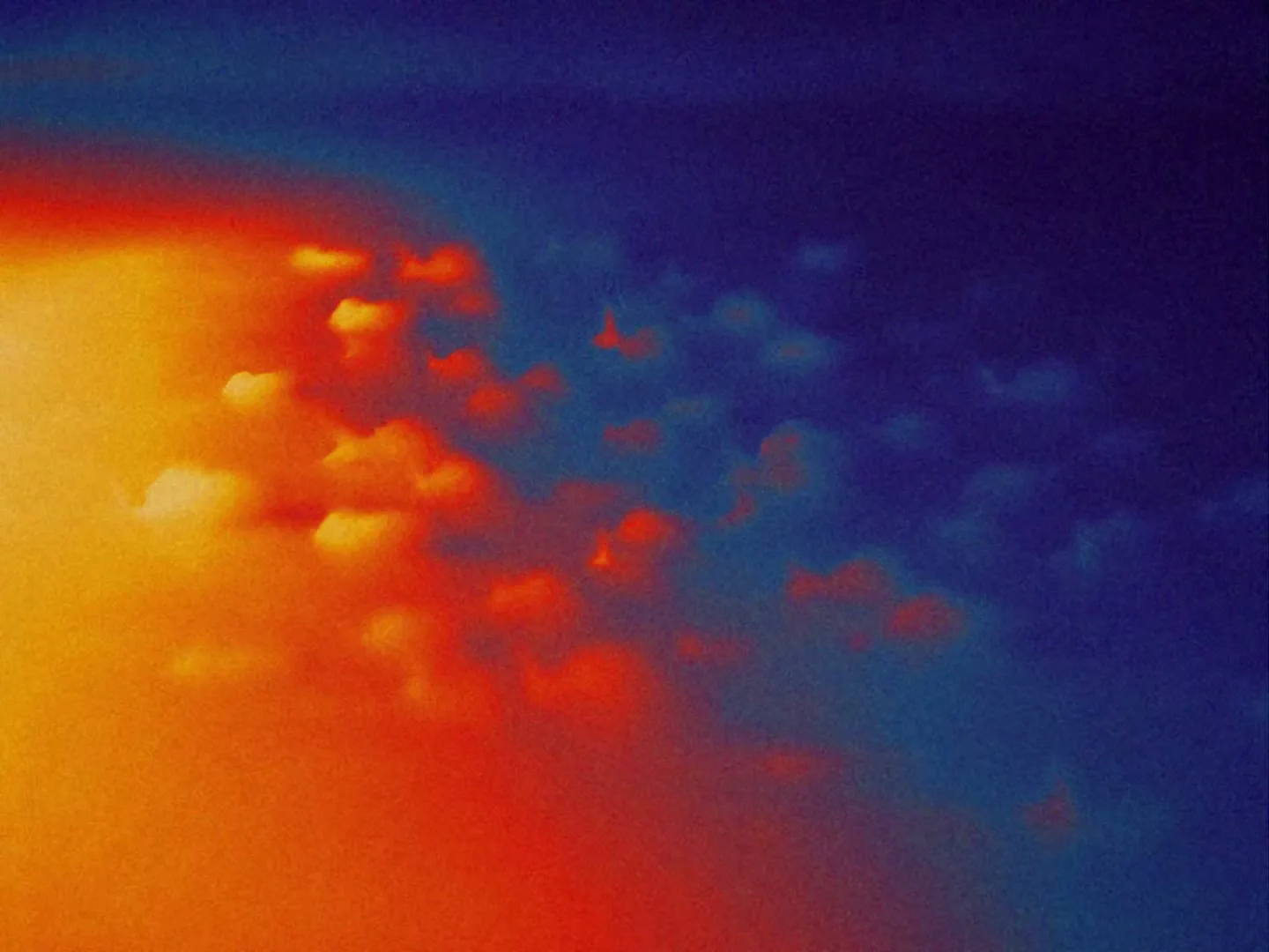 Abstract shot of orange and blue colors blending together with small, bright, glowing shapes moving across the screen.