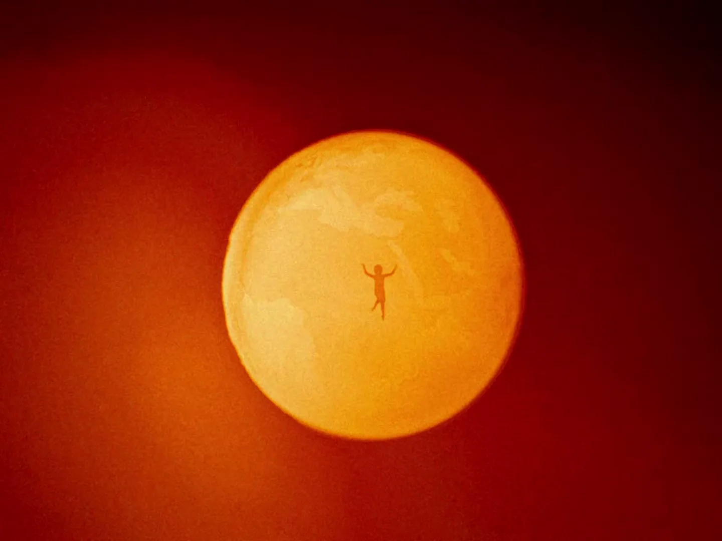 A tiny human silhouette floats in the center of a large, glowing orange sphere, against a deep red background, symbolizing extreme heat.