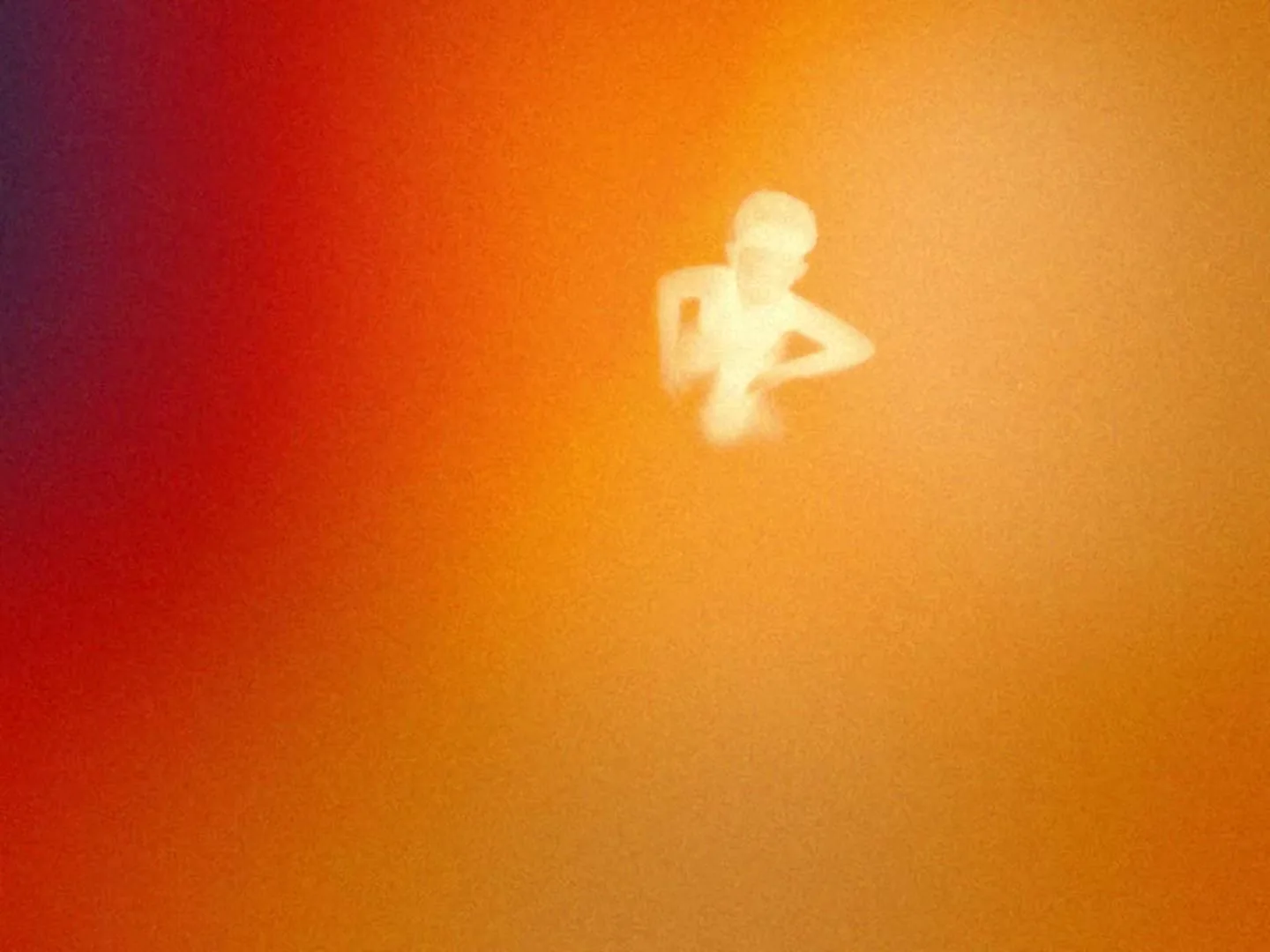 A blurry, glowing white figure of a person is seen from above, against a gradient background of red, orange, and yellow.