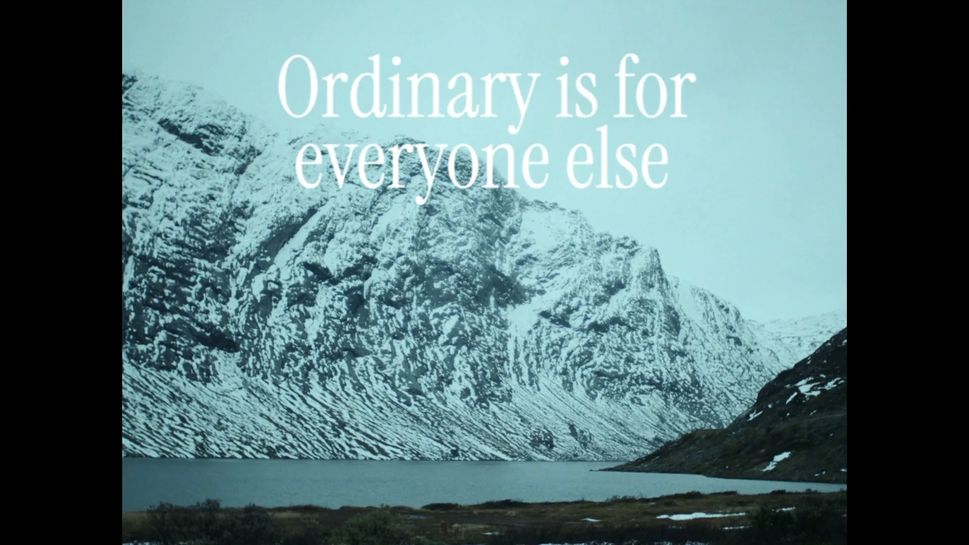 White text on screen reads "Ordinary is for everyone else" over a wide shot of a snowy mountain range and a lake.