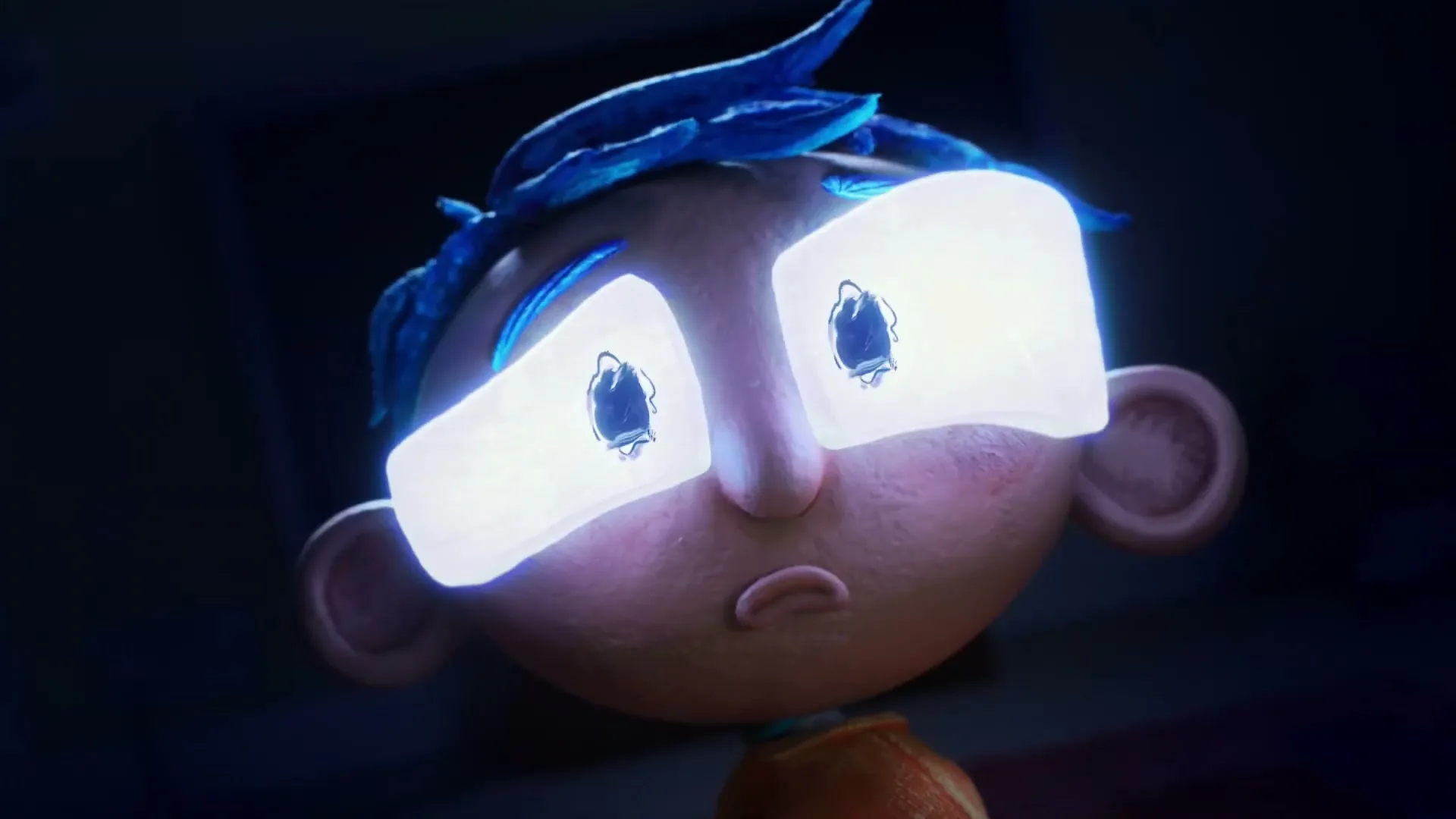 A claymation boy with blue hair and glowing white eyes stares blankly, illuminated by a screen in a dark room.