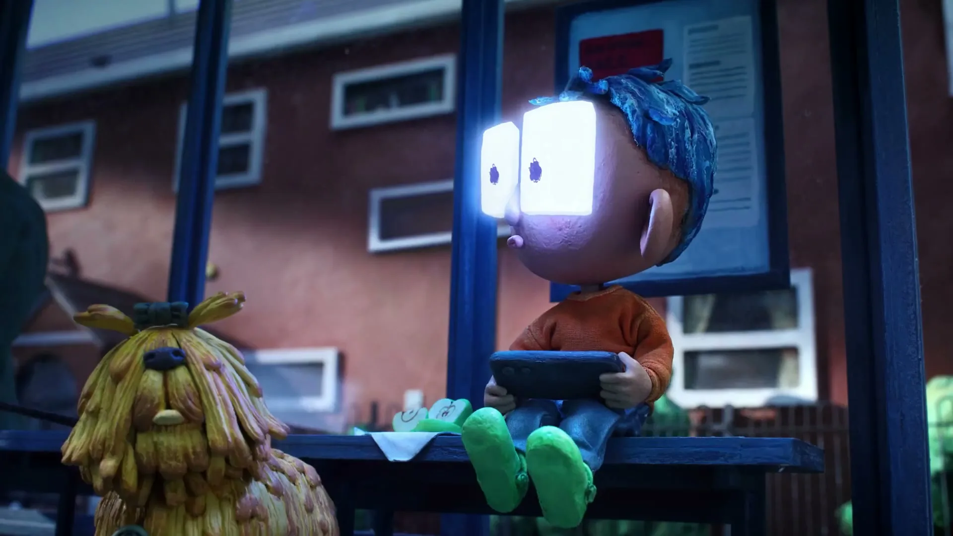 A claymation boy with glowing rectangular eyes sits on a bench next to a shaggy dog, holding a tablet at night.