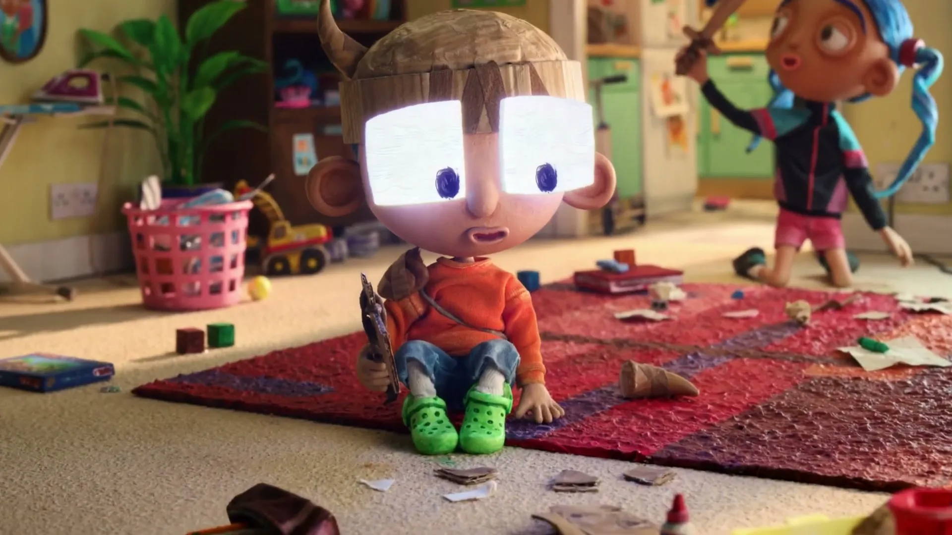 A young boy with a Viking helmet and glowing eyes sits on a rug, while a girl with blue pigtails plays with a sword in a messy living room.