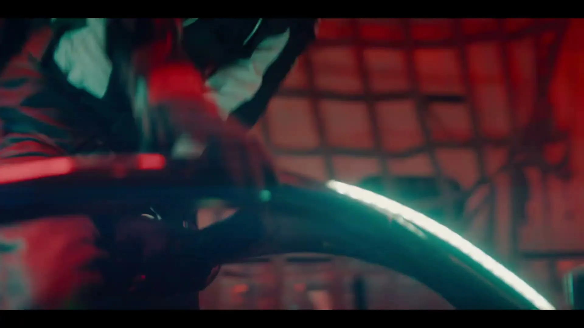 A male Formula E driver in a racing suit is seen from a low angle, getting into his car in a dimly lit garage.