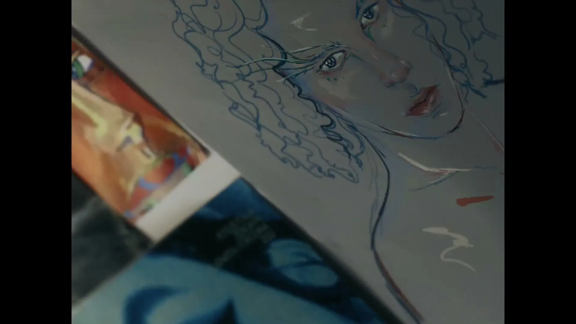 A close-up shot of a drawing of a person with curly hair and a thoughtful expression, lying on a surface with other papers.