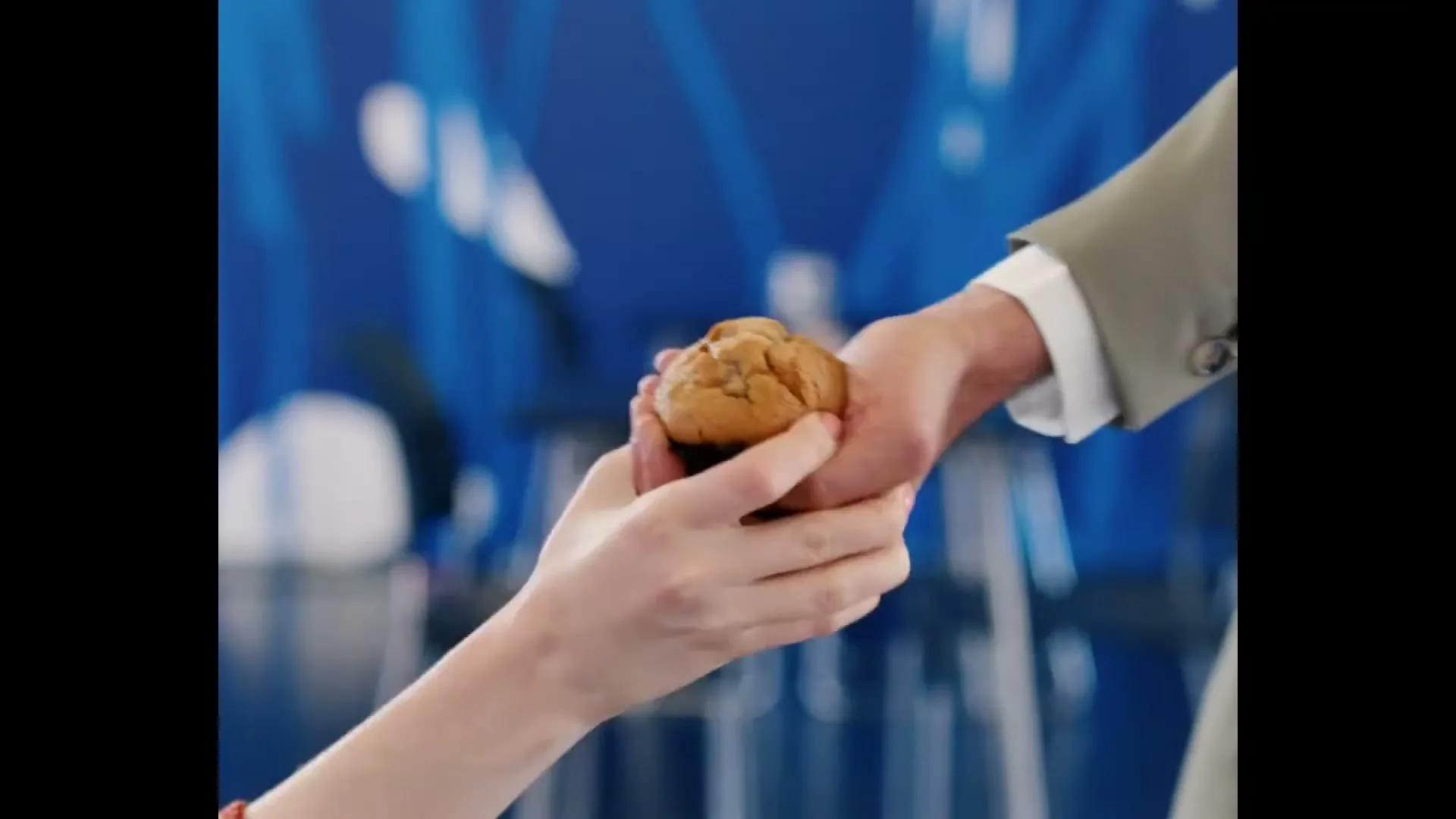A child's hand takes a muffin from an adult's hand, then a young boy with red hair covers his ears and screams in an art gallery.