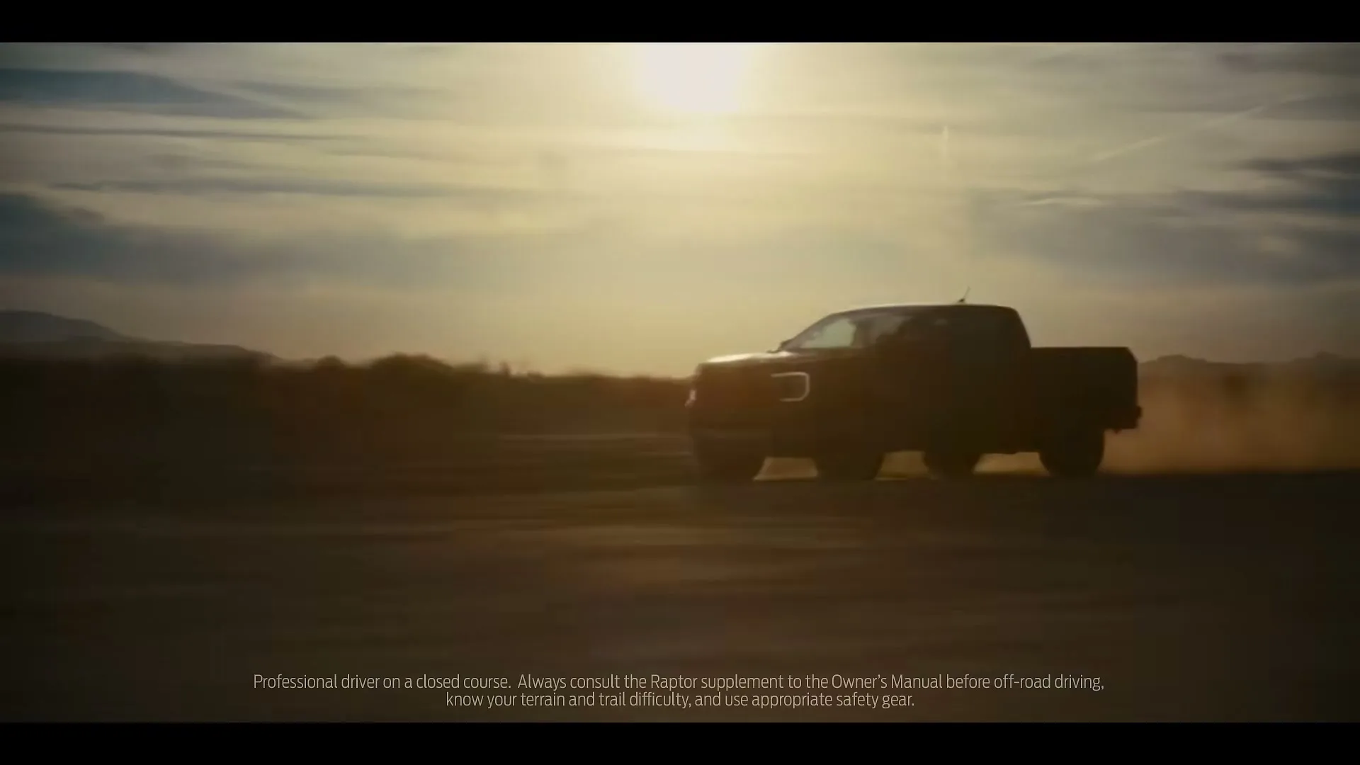 A Ford Ranger pickup truck drives through a dusty desert landscape at sunset, kicking up dirt as it moves across the frame.