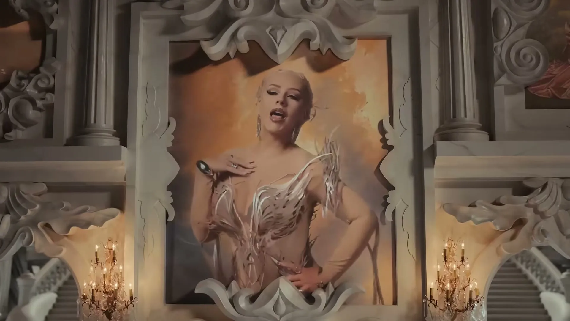 Christina Aguilera, dressed in an elaborate gown, sings dramatically from within a large, ornate painting in a grand, palatial setting.