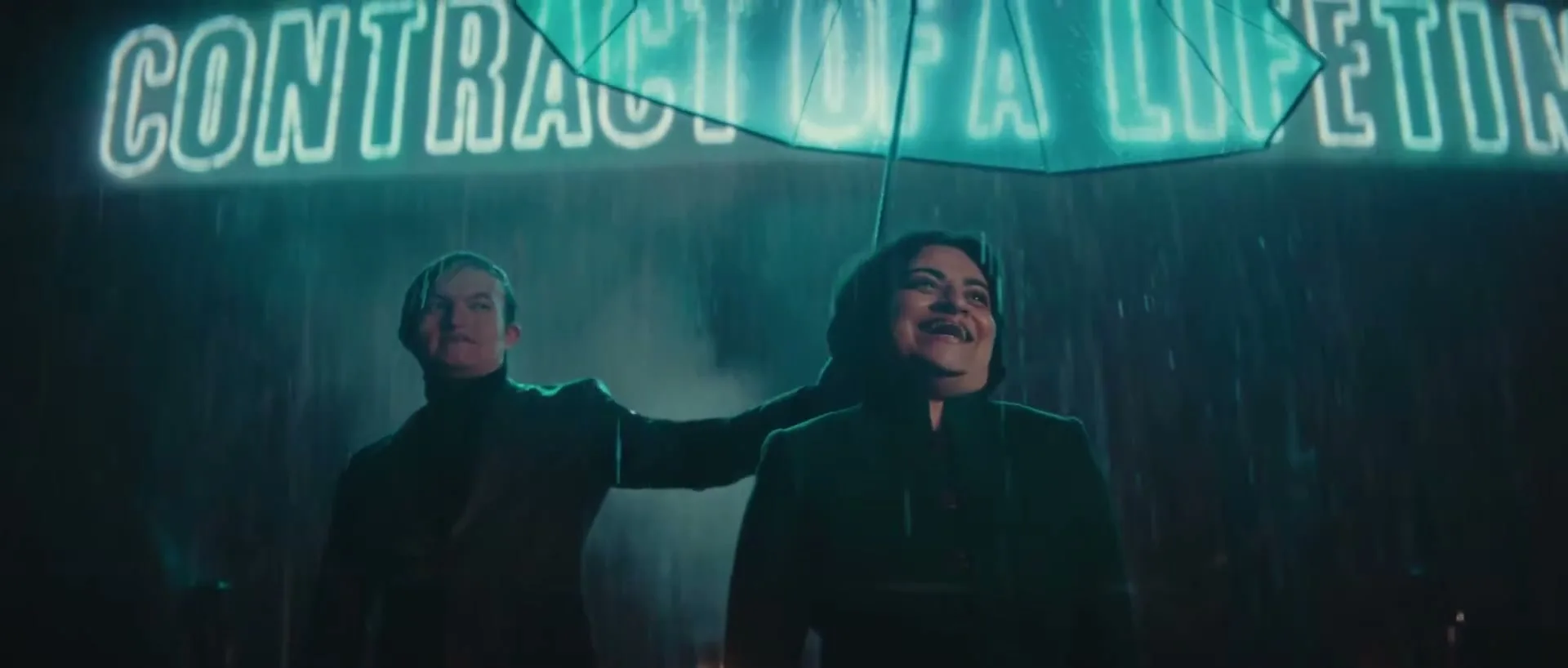 Two people, a man and a woman, stand under a neon green umbrella in the rain, smiling at a neon sign that reads "CONTRACT OF A LIFETIME".