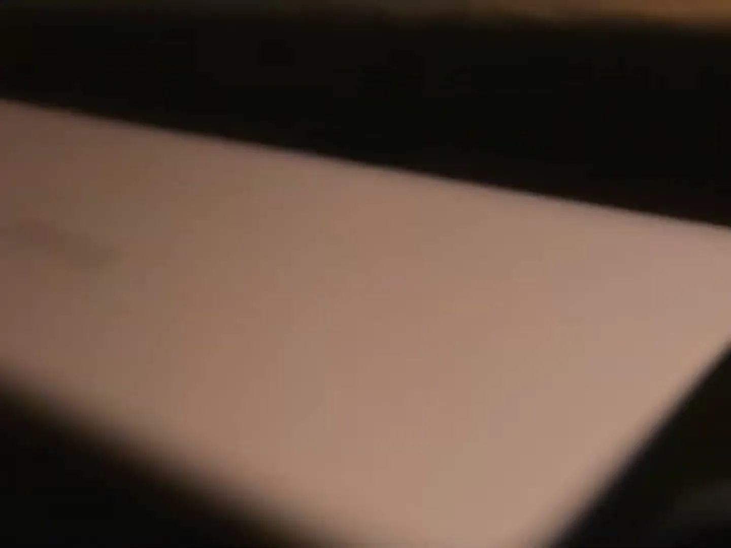 A person's hand opens a white iPad Air box, revealing the device inside, in a dimly lit interior.