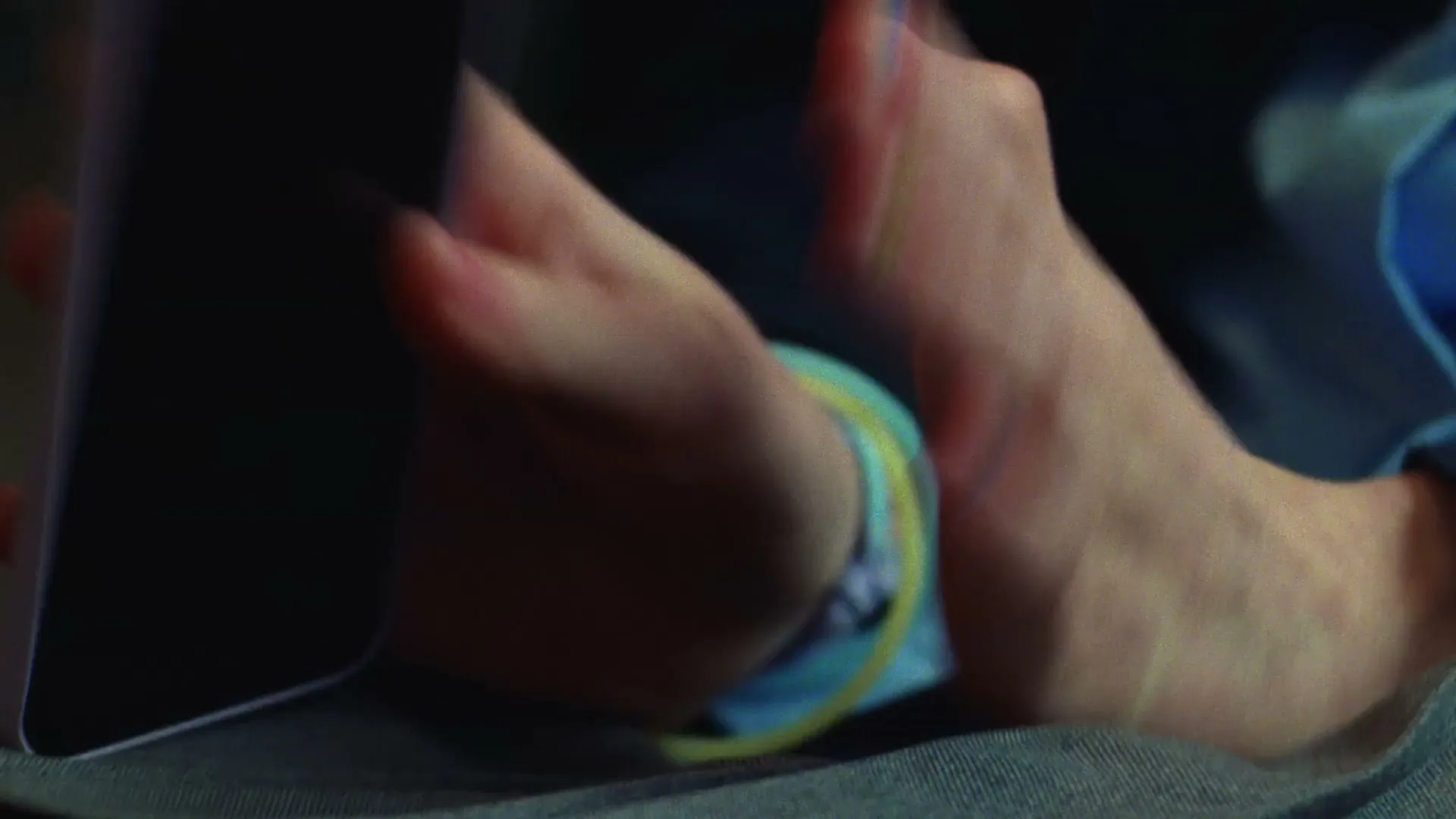 A child's hands with brightly painted fingernails are shown, as they place a white smartphone down on a grey surface.