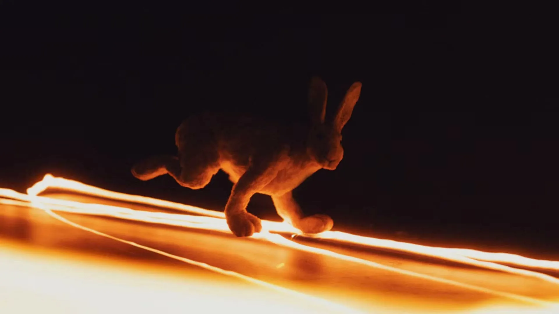 A toy rabbit runs across a dark surface, surrounded by glowing orange light trails, suggesting movement through a fiery landscape.