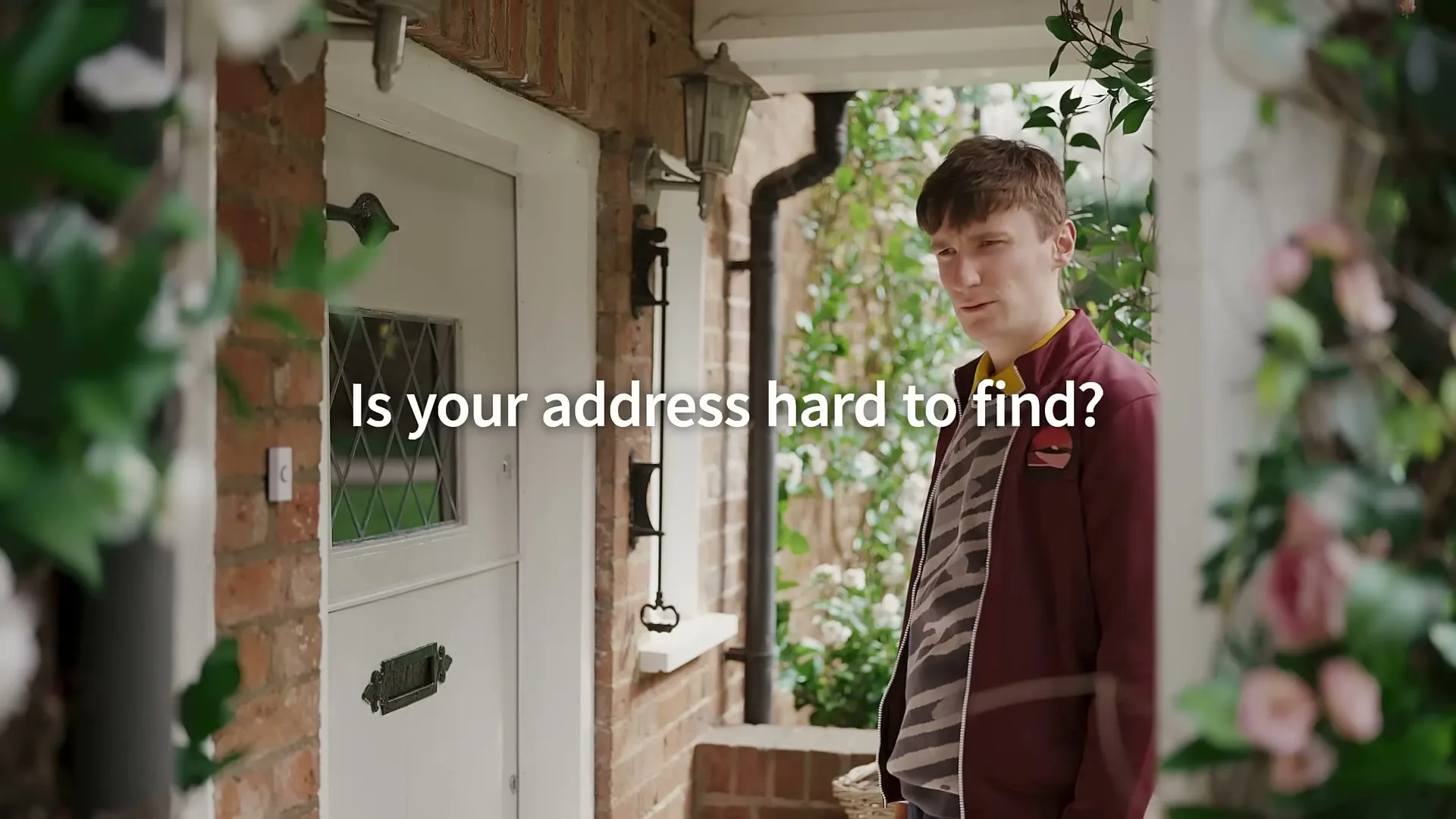 A young man in a maroon jacket and striped shirt stands on a porch, looking at the camera, with text overlay about addresses.