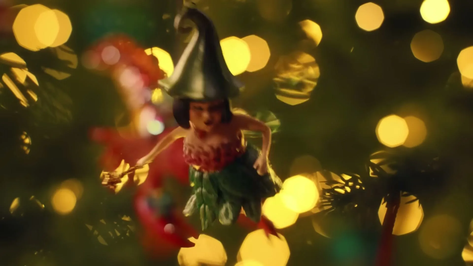 A close-up shot of a fairy Christmas ornament hanging on a Christmas tree, with blurred lights in the background.