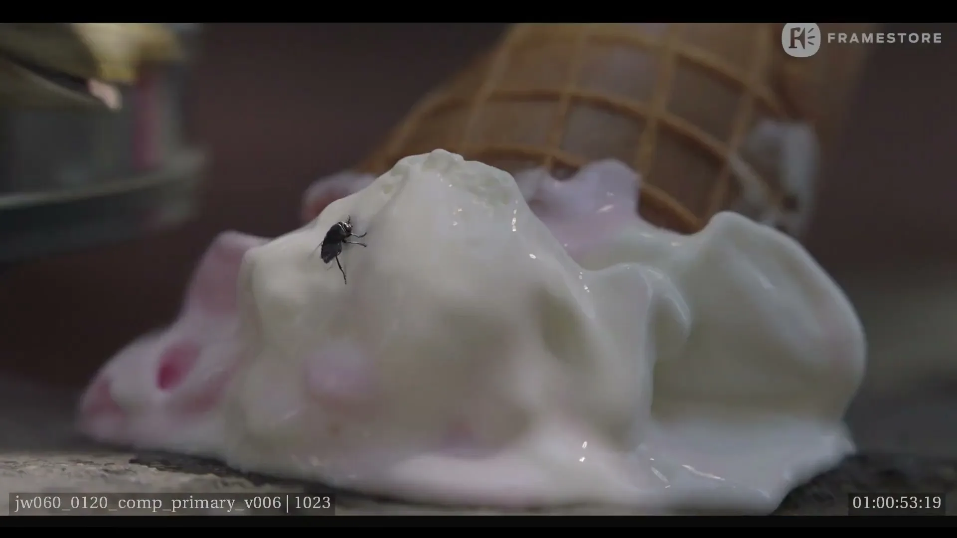 A fly crawls on a scoop of melting ice cream that has fallen out of a waffle cone onto a surface.