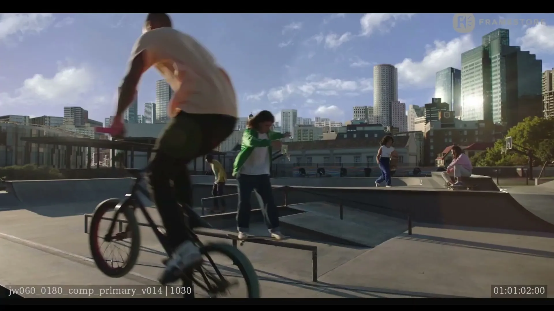 A diverse group of teens and young adults skateboard and bike in a sunny urban skatepark with a city skyline in the background.