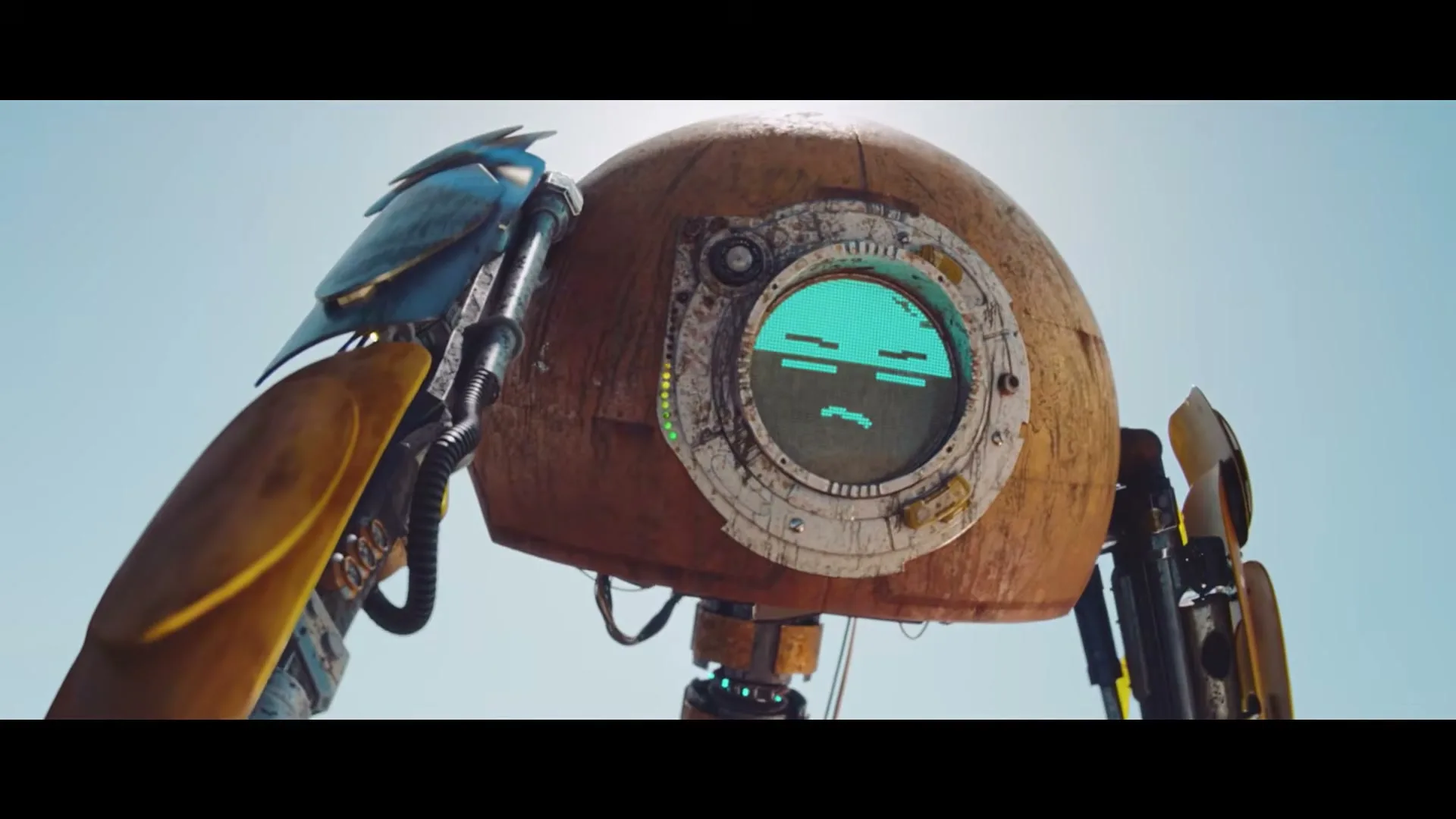 A rusty, dome-headed robot with a blue bird perched on its shoulder stands under a bright sky, its screen face showing a sad expression.