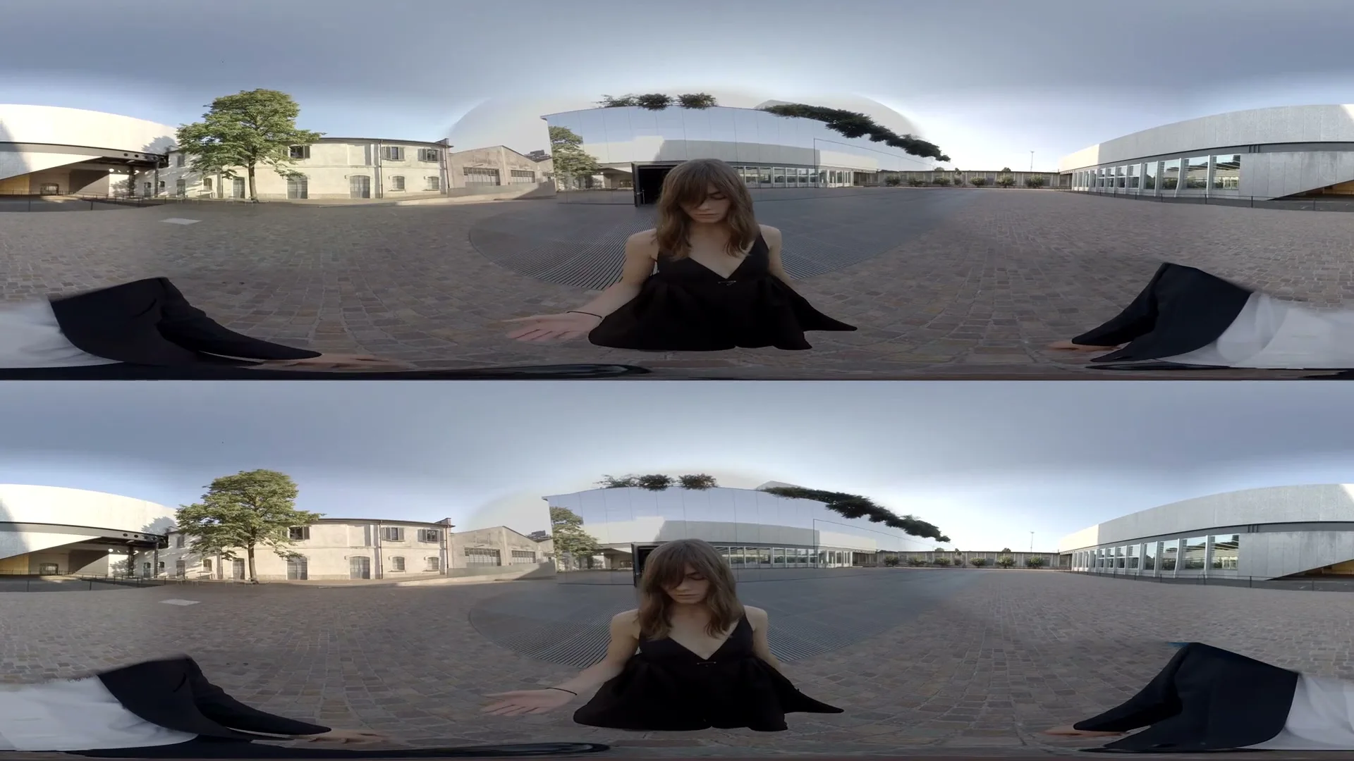 A young woman in a black dress sits and stands in a 360-degree view of a modern architectural plaza with reflective buildings and trees under a bright sky.